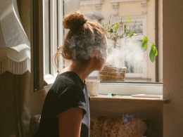 woman smoking while look through the window