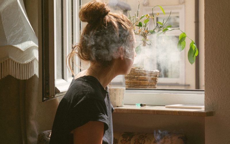 woman smoking while look through the window