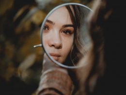 woman holding magnifying glass with brown liquid