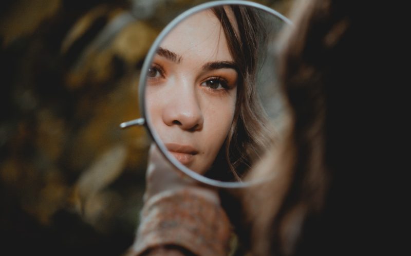 woman holding magnifying glass with brown liquid